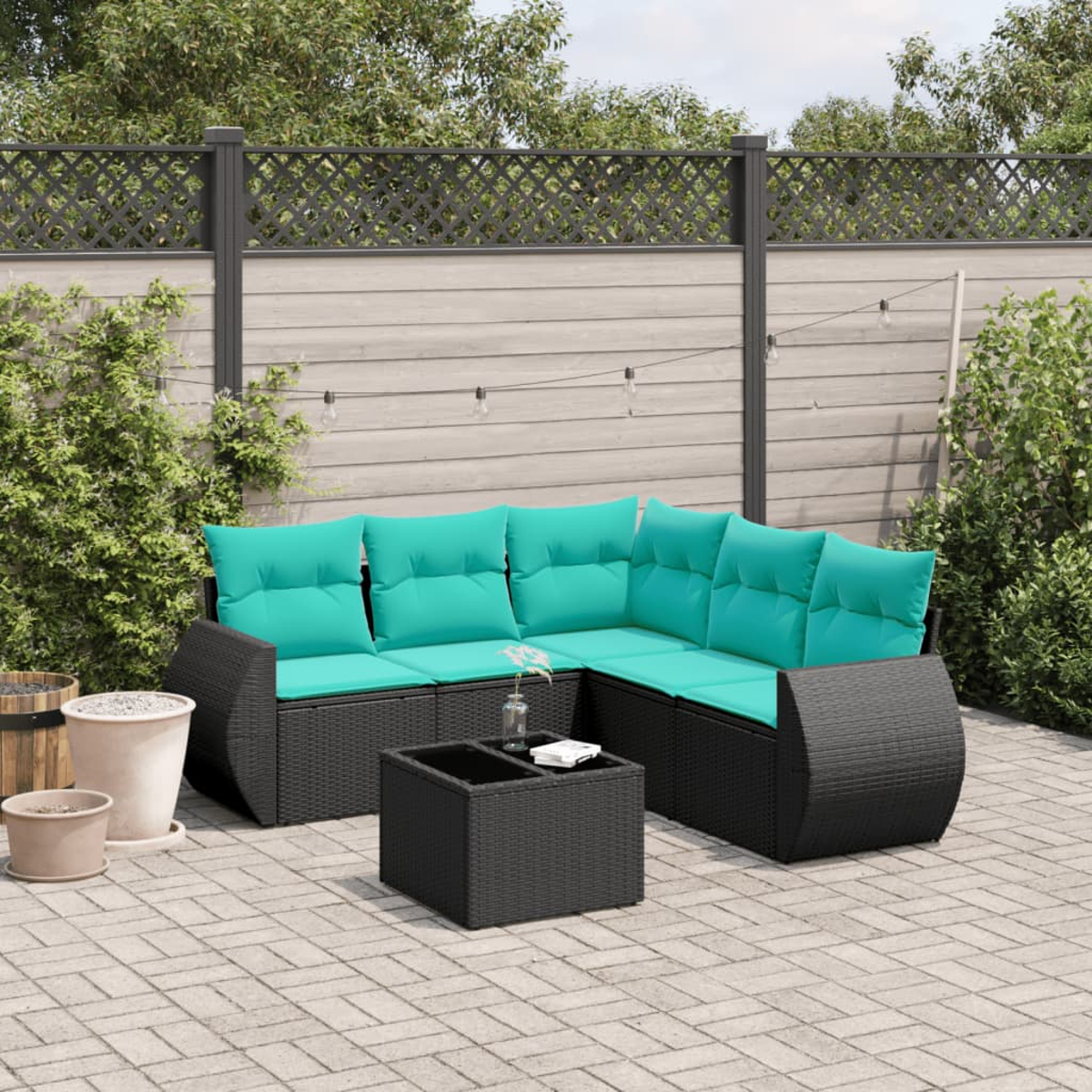 Outdoor-Ecksofa mit türkisfarbenen Kissen. Ein schwarzer gewebter Tisch und Pflanzgefäße davor. Im Hintergrund ein Holzzaun.