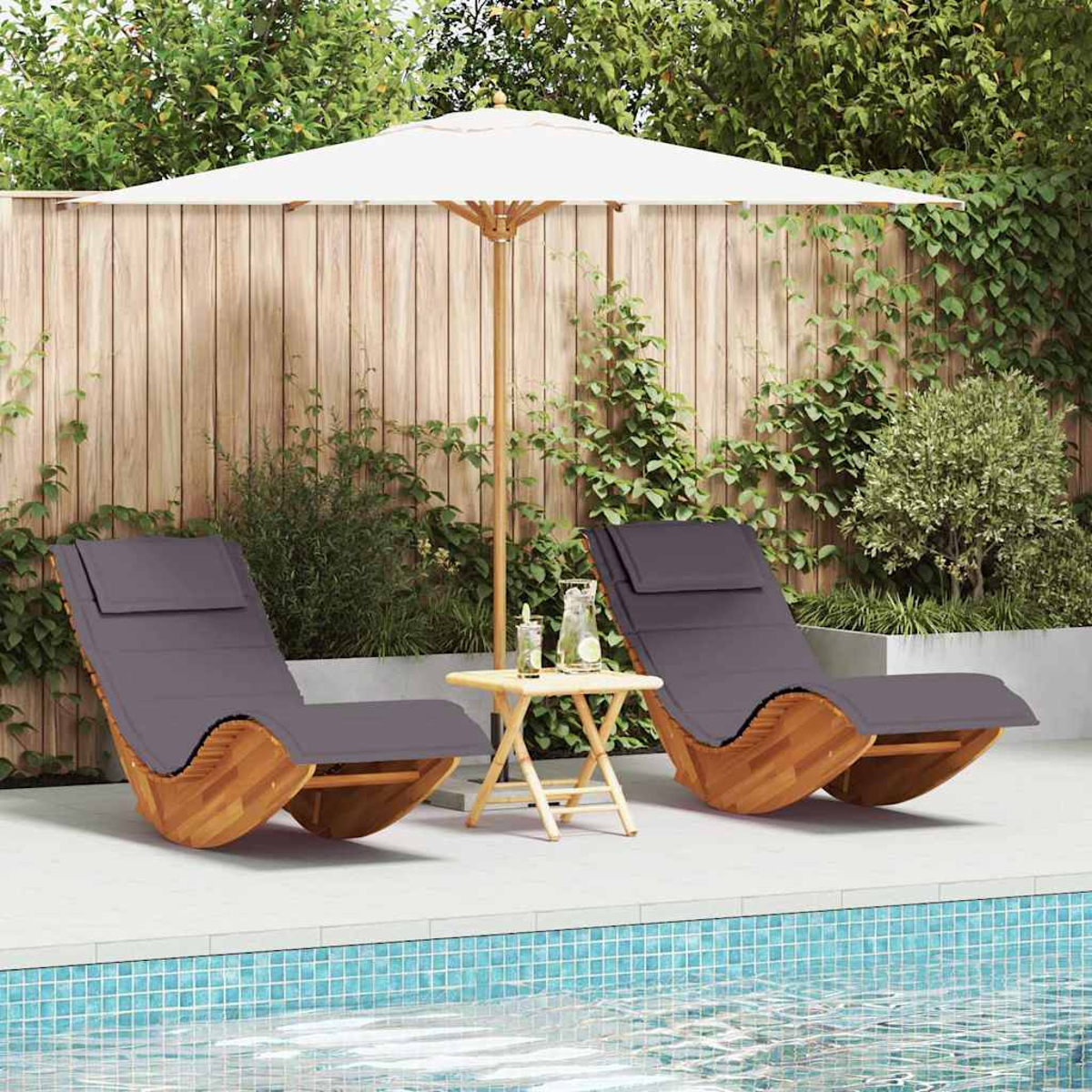 Zwei graue Liegestühle am Pool, ein kleiner Tisch mit Getränken und ein weißer Sonnenschirm in einem Garten.