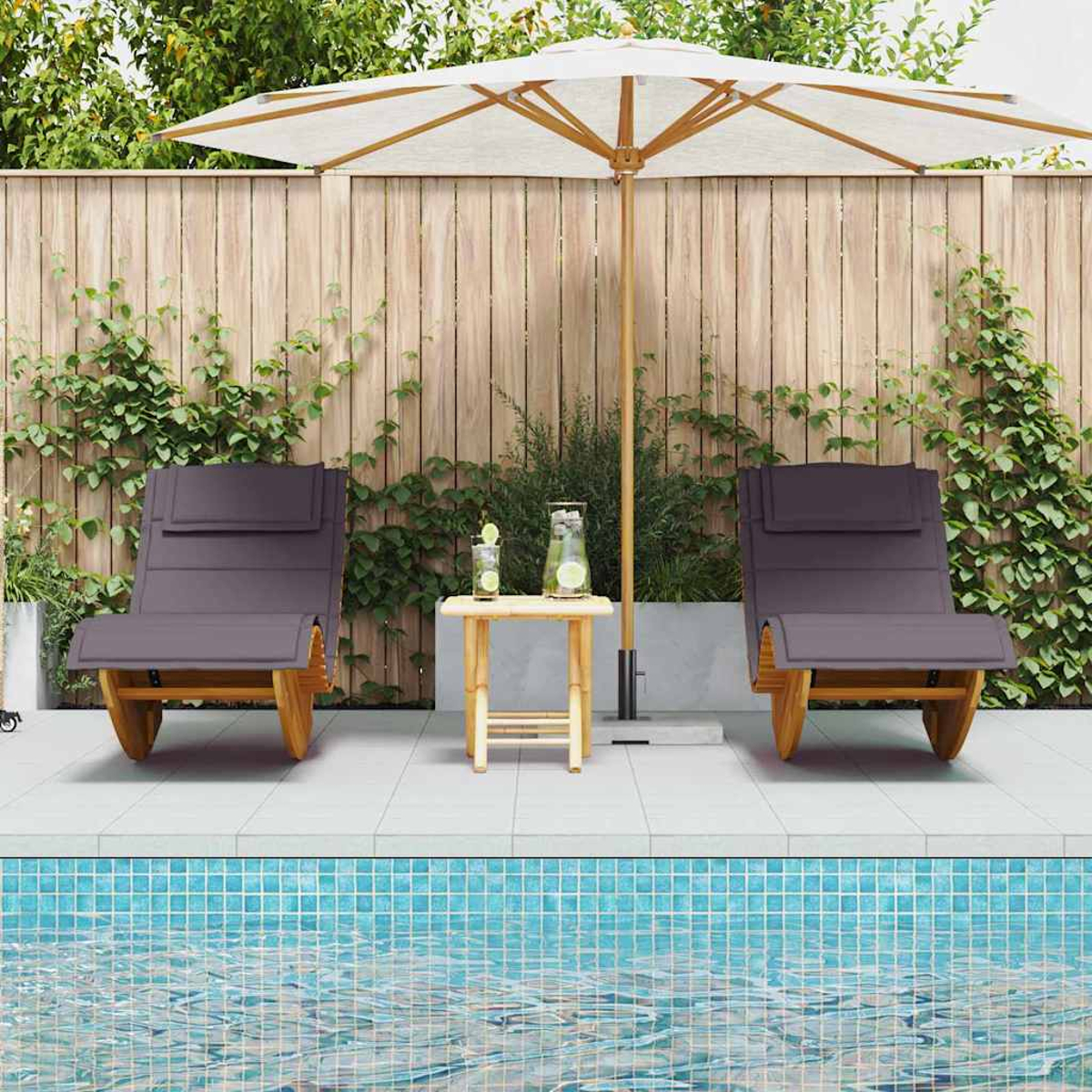 Zwei graue Liegestühle an einem Pool, mit einem kleinen Tisch und einem Sonnenschirm. Ein Holzzaun und Pflanzen sind im Hintergrund.