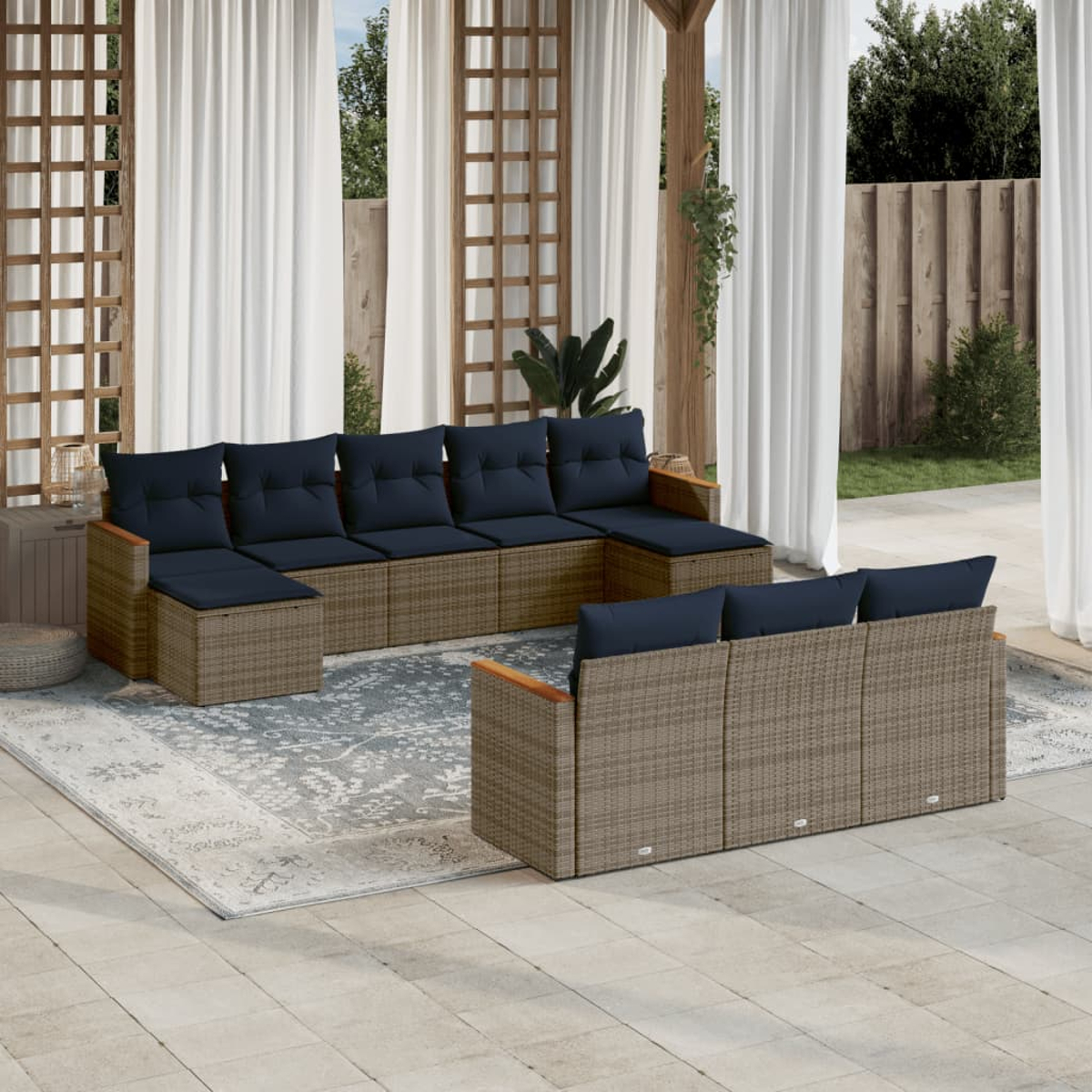 Ein Sitzbereich im Freien mit gewebten Korbmöbeln. Auf einem gemusterten Teppich steht ein großes Ecksofa mit marineblauen Kissen.