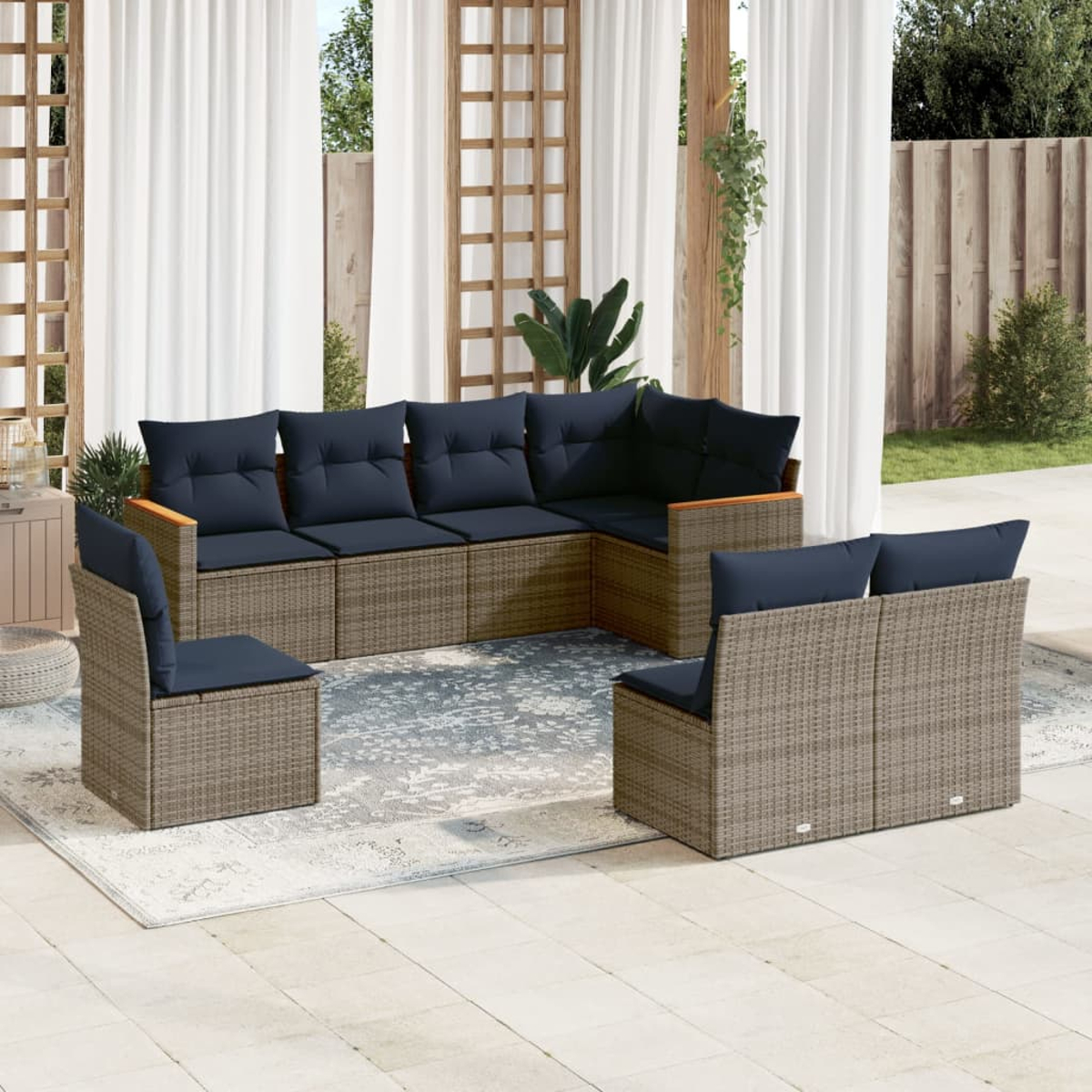 Outdoor-Wicker-Möbelset mit marineblauen Kissen. Es umfasst ein Ecksofa, zwei Stühle und einen Teppich vor weißem Vorhanghintergrund.