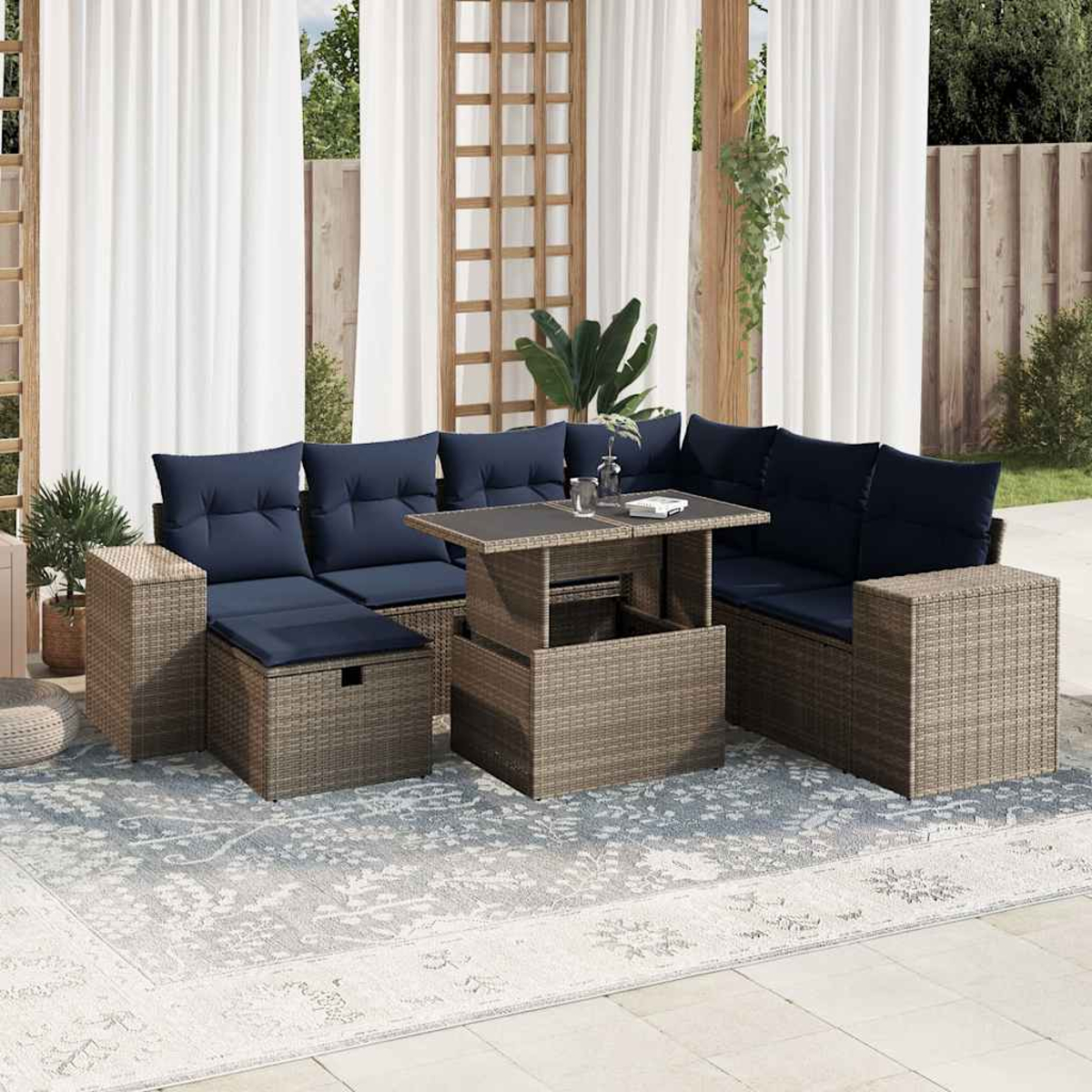 Seccional exterior con cojines azules y mesa de centro. Cortinas blancas y una alfombra estampada en el patio.