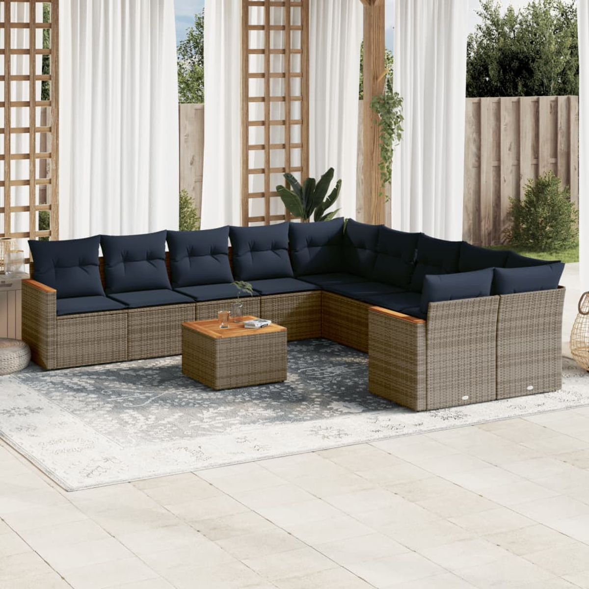 Außenbereich mit Ecksofa, Holztisch und gemustertem Teppich. Weiße Vorhänge und Holzgitter im Hintergrund.