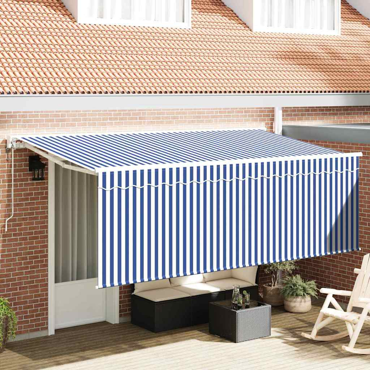 Eine Terrasse mit einer blau-weiß gestreiften Markise. Es gibt eine Sitzecke mit einem schwarzen Tisch und einem Schaukelstuhl.