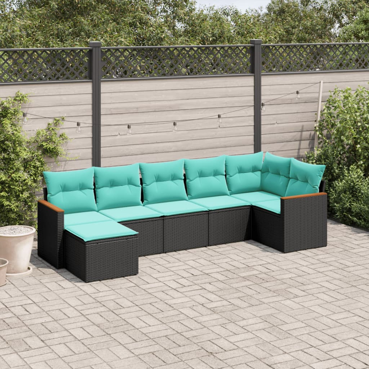 Outdoor-Sofa mit schwarzem Korbgeflecht, türkisfarbenen Kissen und Holzarmlehnen steht auf einer gepflasterten Terrasse.