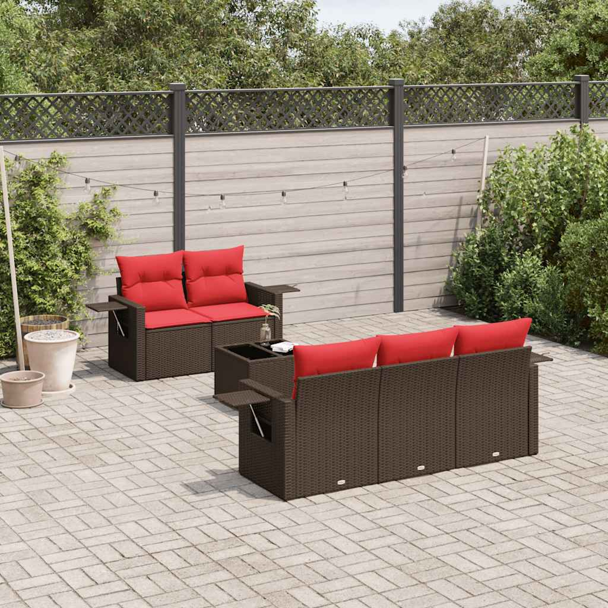 Outdoor-Terrassenset mit braunen Korbmöbeln und roten Kissen. Enthält ein Liebesnest, ein Sofa und einen kleinen Tisch auf einer Ziegelterrasse.