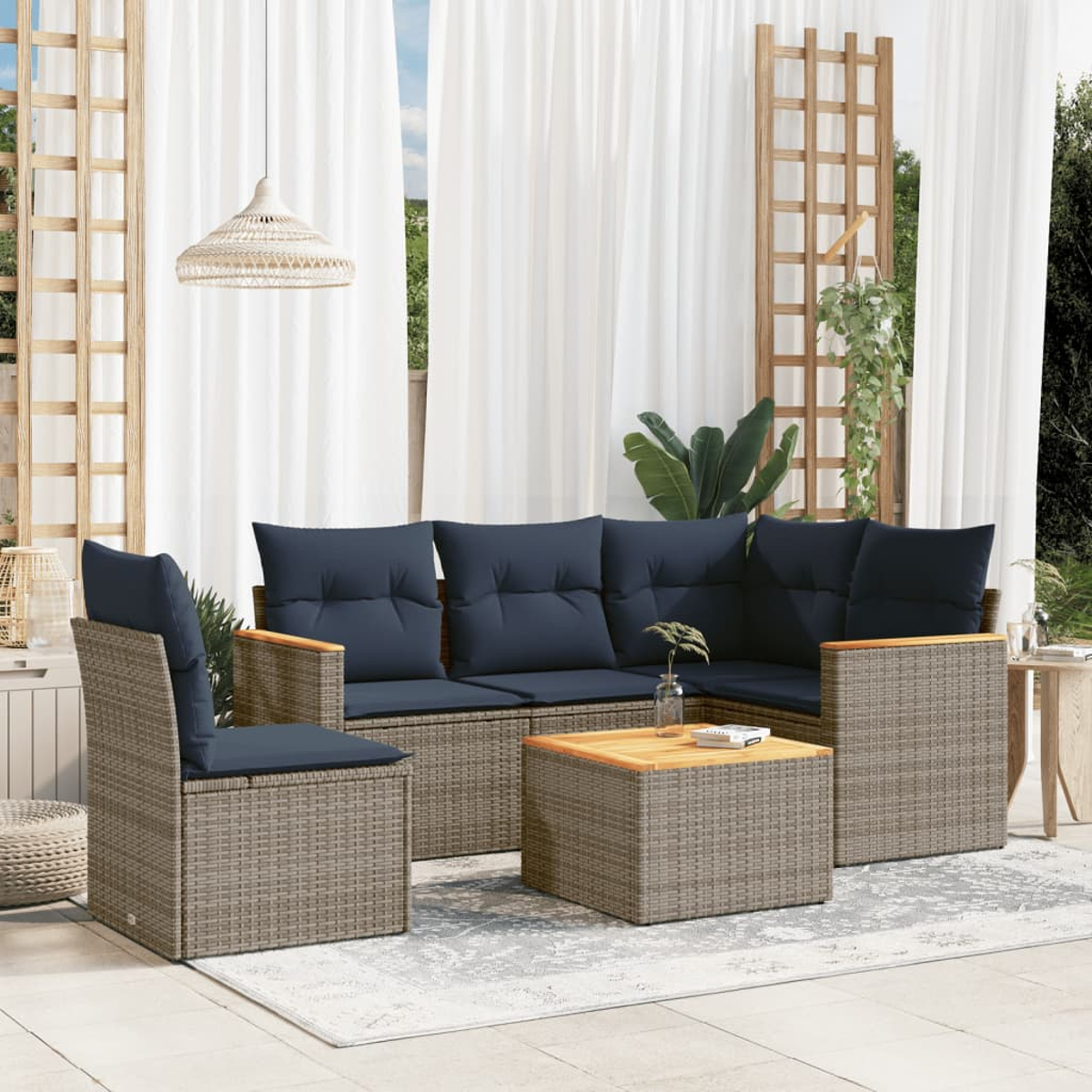 Garten-Sitzgruppe mit marineblauen Kissen und Holzakzenten. Ein Rattanstuhl und ein Ecksofa stehen auf einem Teppich. Weiße Vorhänge im Hintergrund.