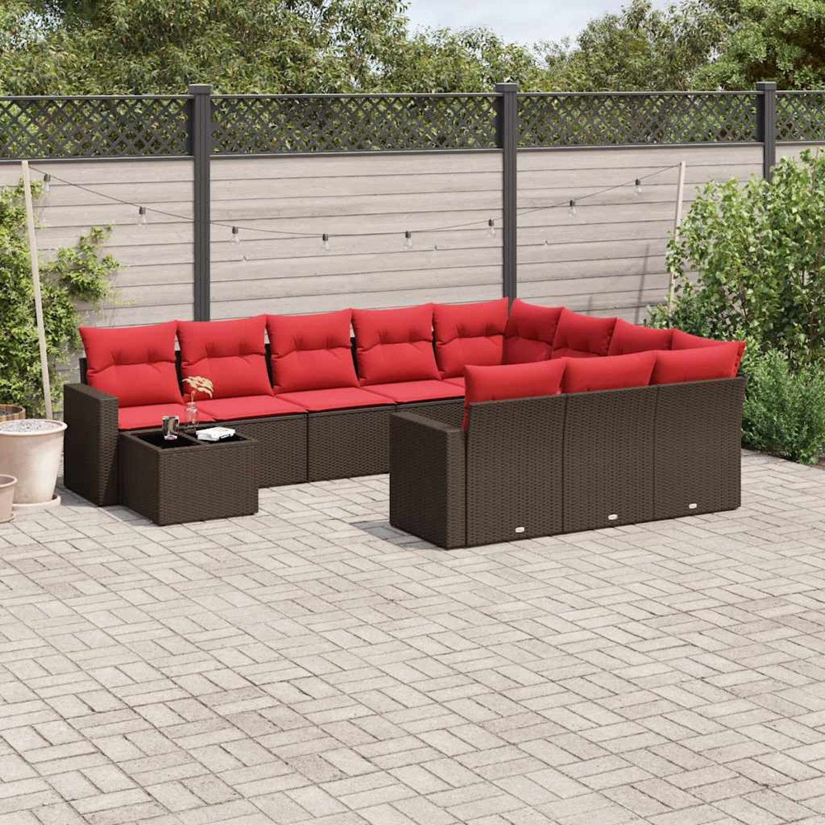 Outdoor-Ecksofa mit roten Kissen und einem kleinen Tisch. Die Kulisse ist eine Terrasse mit Zaun und Grün im Hintergrund.