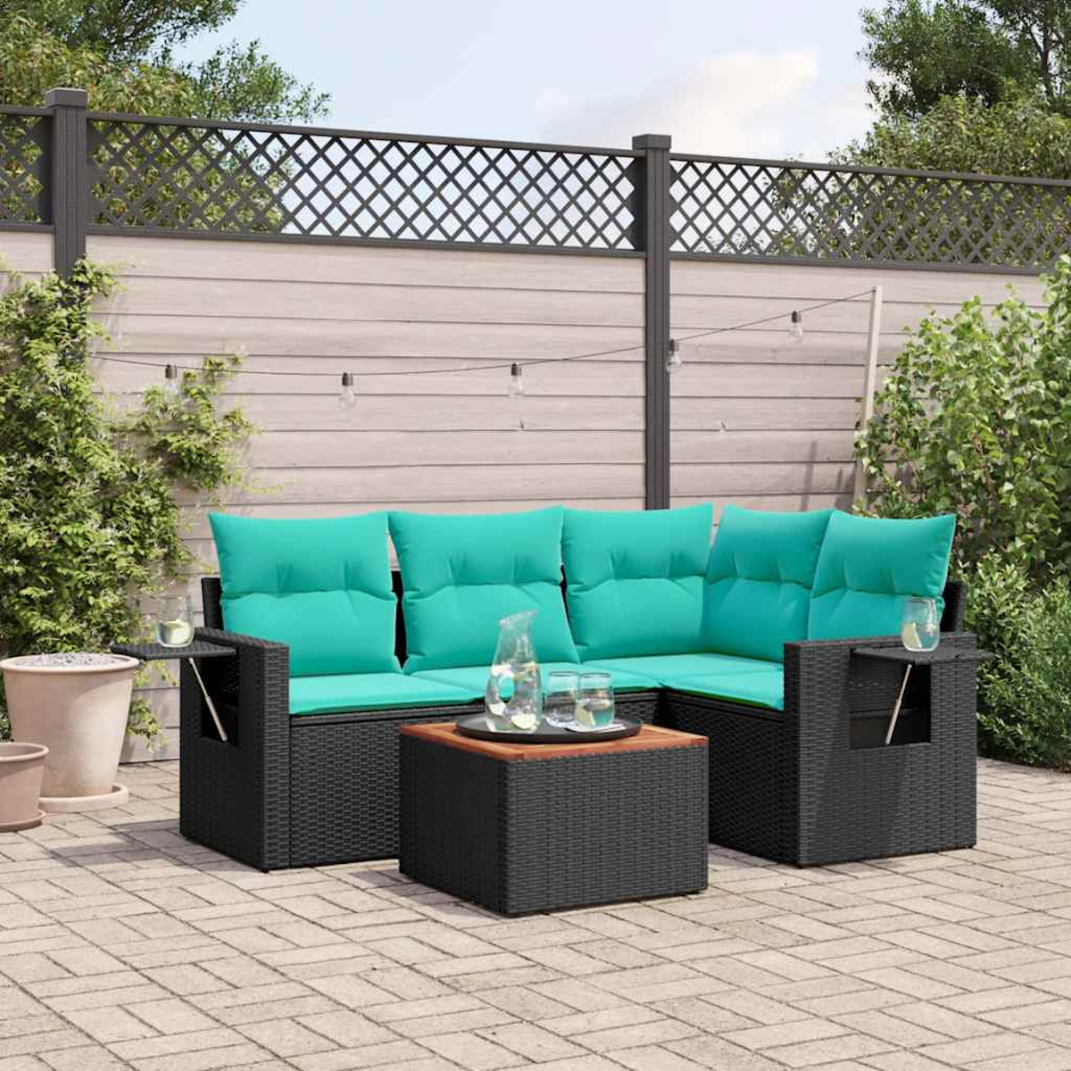 Outdoor-Ecksofa mit tealfarbenen Kissen, kleinem Tisch, Gläsern und Wasserkrug auf einer Backstein-Terrasse.