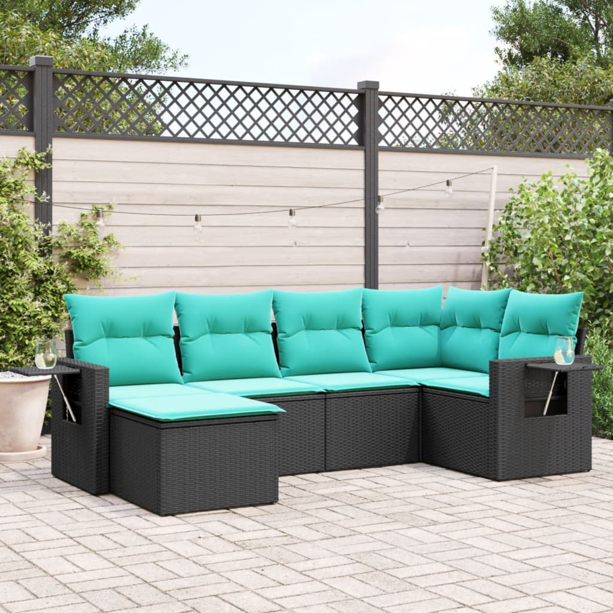 Ein schwarzes Outdoor-Ecksofa aus Korbgeflecht mit türkisfarbenen Kissen steht auf einer Backstein-Terrasse. Ein Gitterzaun und grünes Laub befinden sich im Hintergrund.
