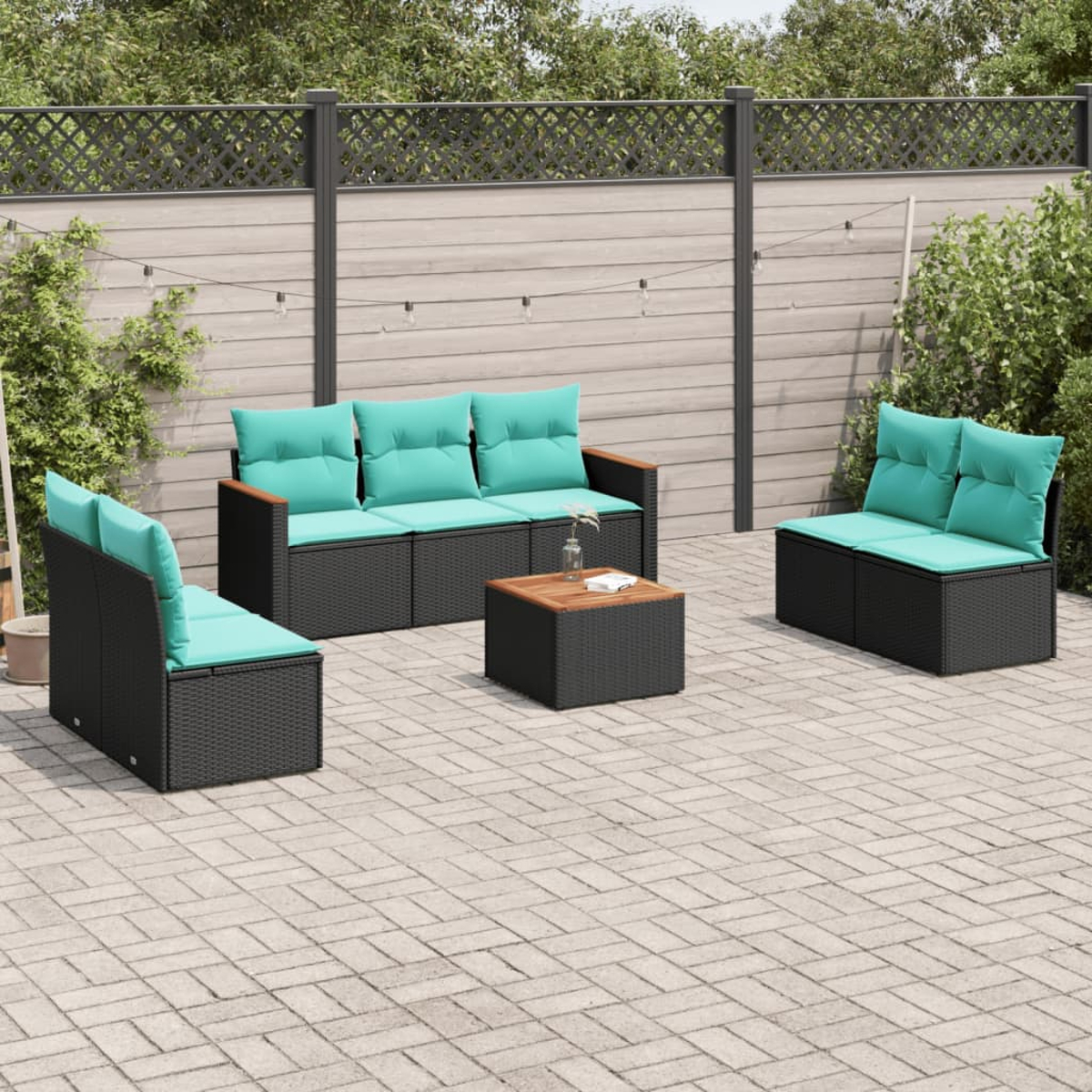 Gartenmöbel-Set mit schwarzem Korbmöbeln und türkisfarbenen Kissen. Enthält Sofa, Stühle und einen Tisch auf einer gepflasterten Terrasse.