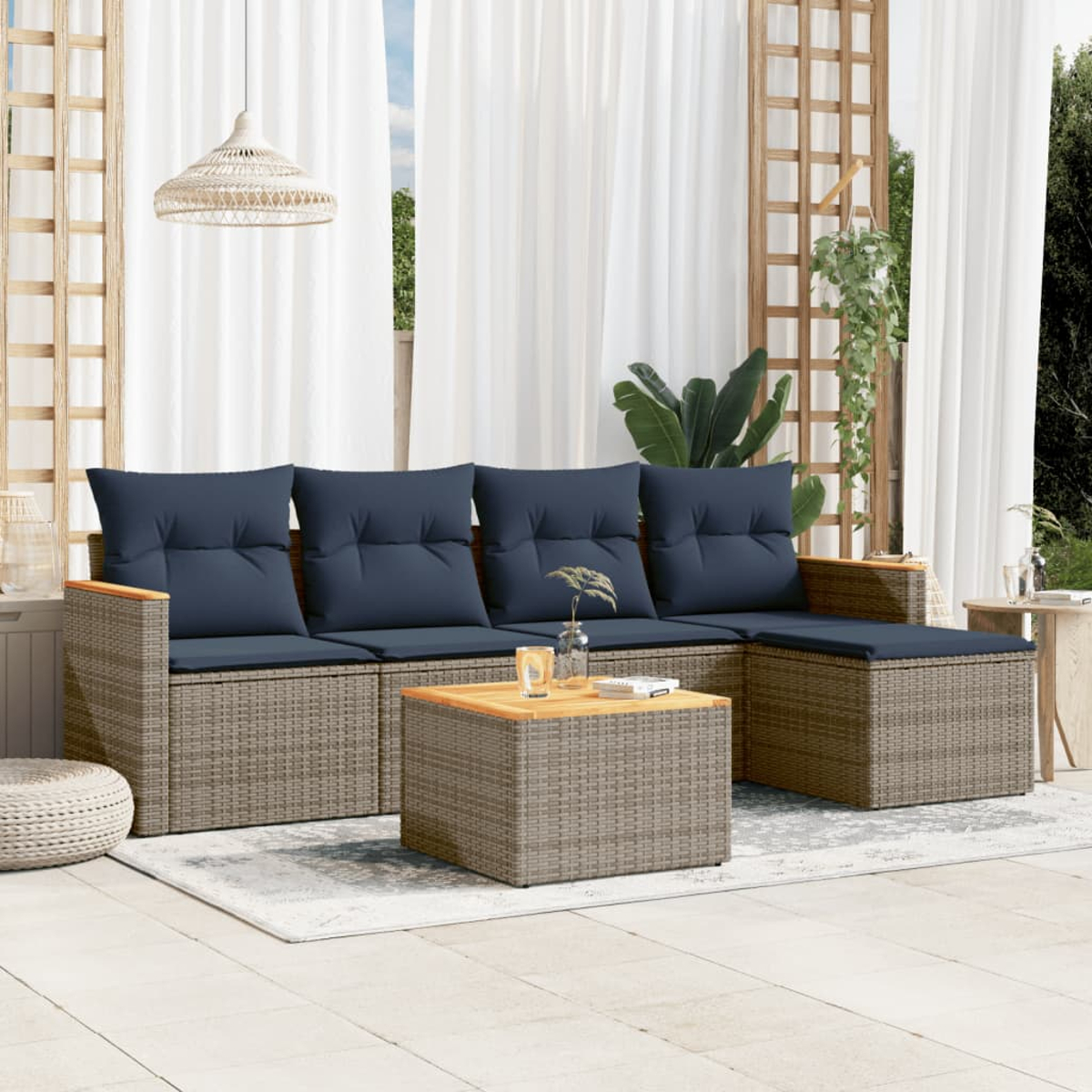 Garten-Sitzgruppe mit blauen Kissen, Couchtisch und Vorhängen. Ein Rattansofa und -tisch stehen auf einer Terrasse. Eine Lampe hängt darüber.