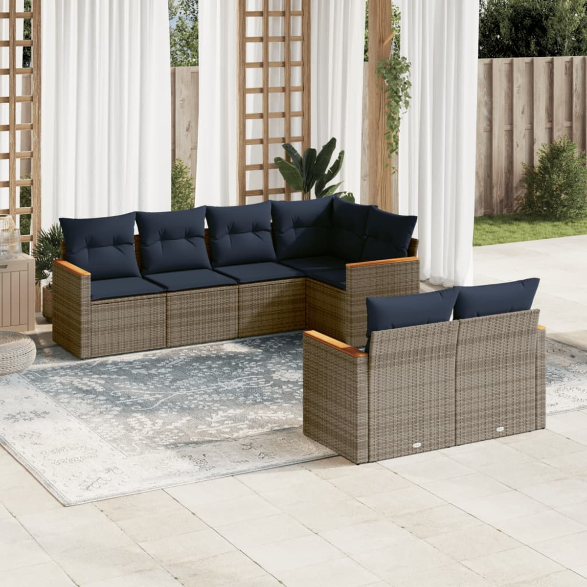 Gartenmöbel mit blauen Kissen auf einer Terrasse. Enthält ein Ecksofa und ein Zweiersofa, auf einem gemusterten Teppich, in der Nähe von Vorhängen.