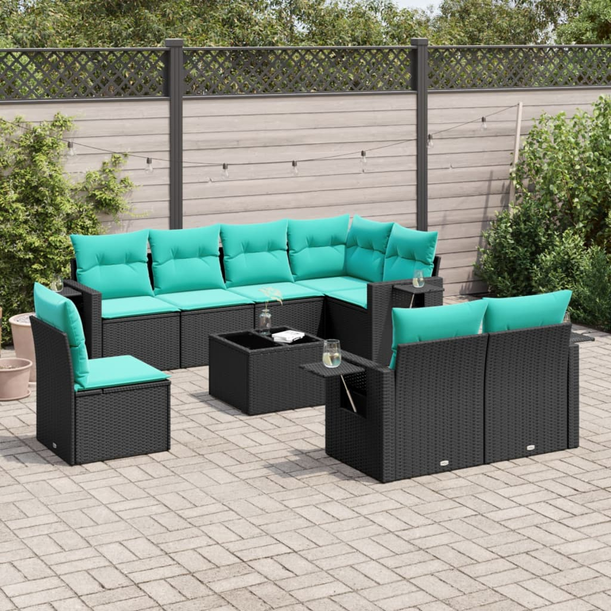 Garten-Terrassenset mit schwarzen Korbmöbeln und türkisfarbenen Kissen. Beinhaltet ein Ecksofa, Stühle und einen Couchtisch auf einer Backsteinterrasse.