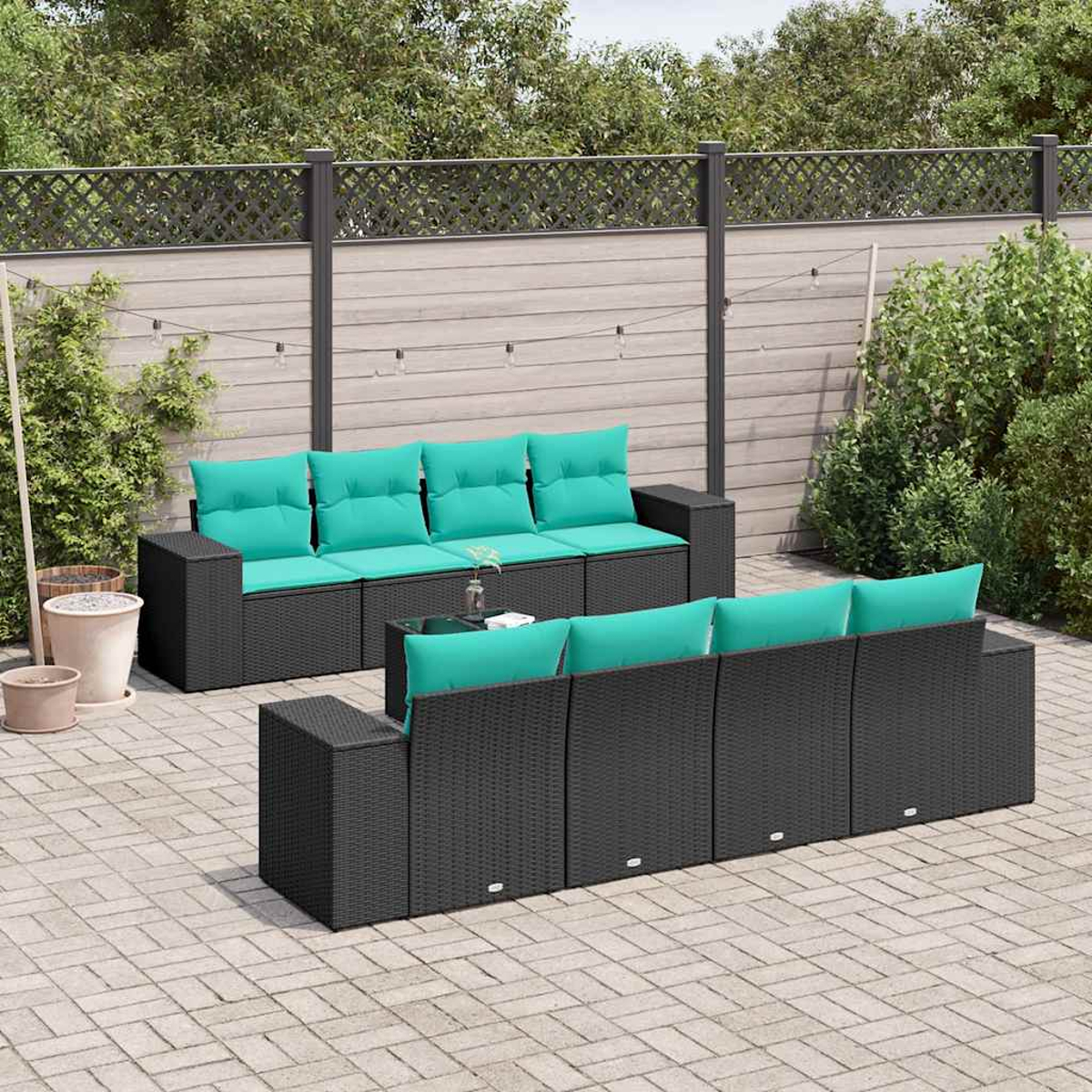 Juego de muebles de patio con marcos de mimbre negro y cojines turquesa. Una mesa con tapa de cristal se encuentra entre los sofás.