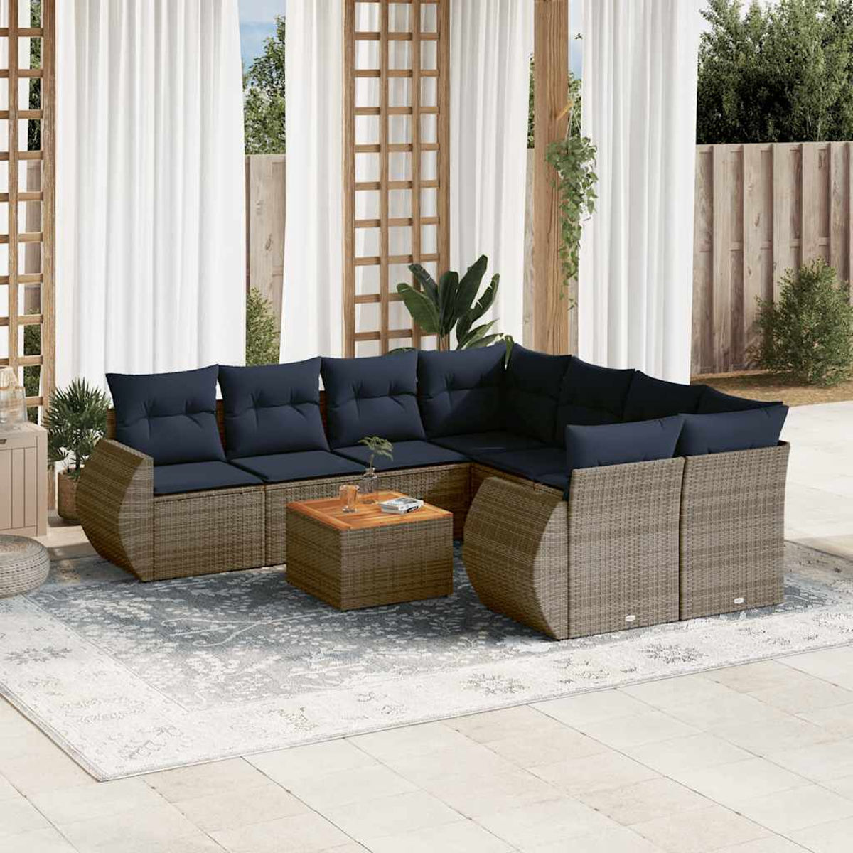 Outdoor-Ecksofa mit marineblauen Kissen und einem Holztisch auf einem gemusterten Teppich, vor weißen Vorhängen.