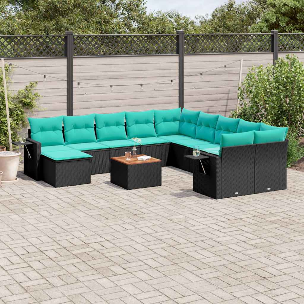 Sofá seccional al aire libre con cojines color turquesa en un patio. Una mesa pequeña al frente. Valla y plantas al fondo.