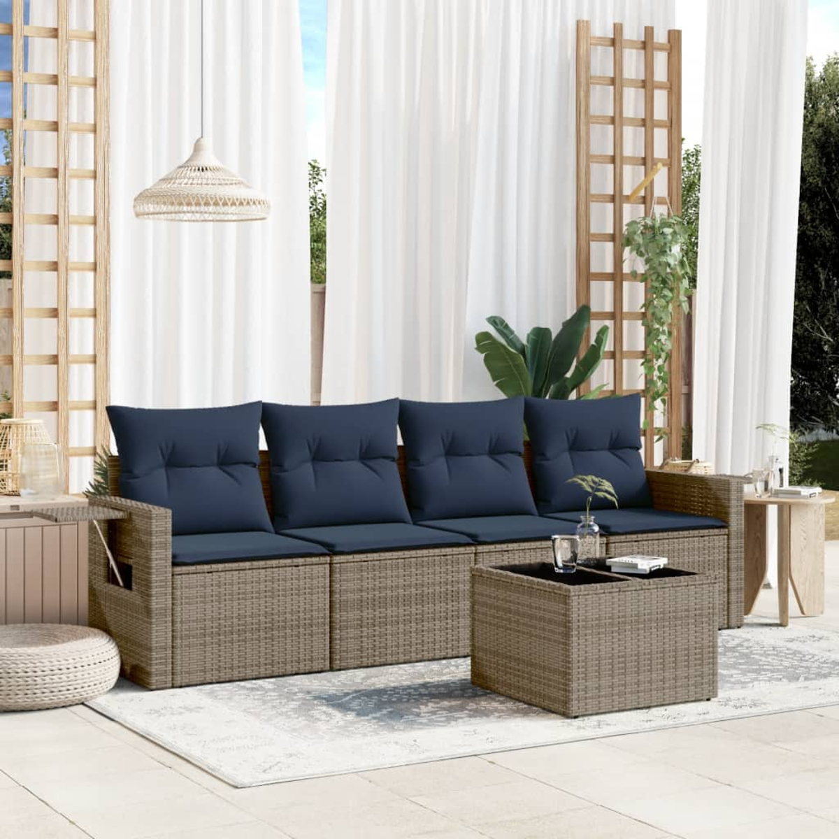 Garten-Sitzgruppe mit blauen Kissen. Beinhaltet Sofa, Couchtisch und Beistelltische. Weiße Vorhänge und eine gewebte Lampe sind sichtbar.