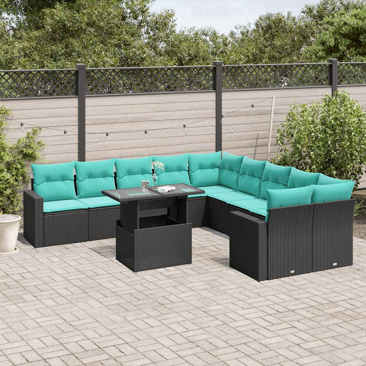 Outdoor-Ecksofa mit türkisfarbenen Kissen und einem schwarzen Tisch auf einer Backstein-Terrasse. Im Hintergrund ein Zaun und Bäume.