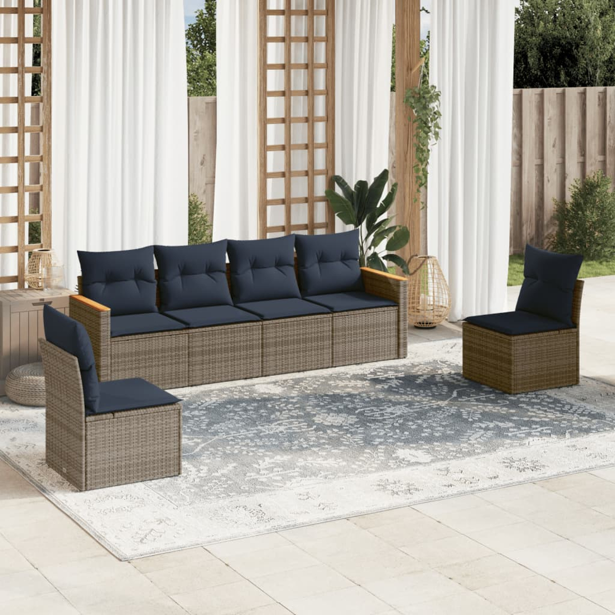 Juego de patio al aire libre con un sofá y dos sillas. Los muebles son grises con cojines azules. Se ve una alfombra y cortinas blancas.