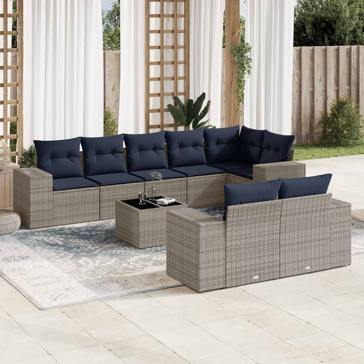 Garten-Sitzgruppe mit marineblauen Kissen, grauem Korbgeflecht und einem Tisch mit Glasplatte. Inklusive Teppich, Vorhängen und Holzgitter.