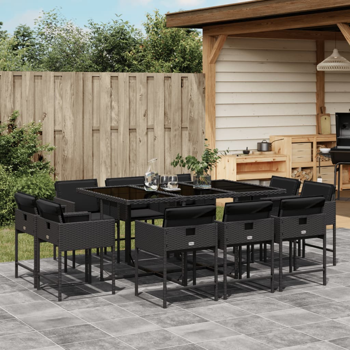 Terrassenset im Freien mit schwarzen Stühlen und Tisch, Glas und Holzzaun im Hintergrund und grünen Bäumen.