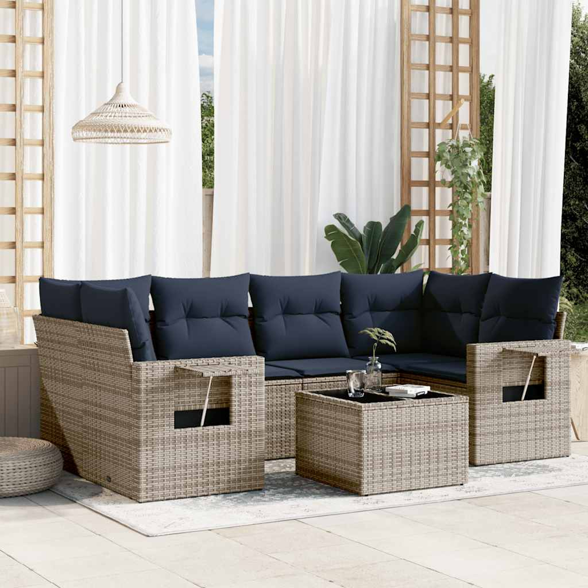 Garten-Sitzgruppe mit marineblauen Kissen. Beige Korbmöbel mit Couchtisch. Weiße Vorhänge und Hängeleuchte im Hintergrund.