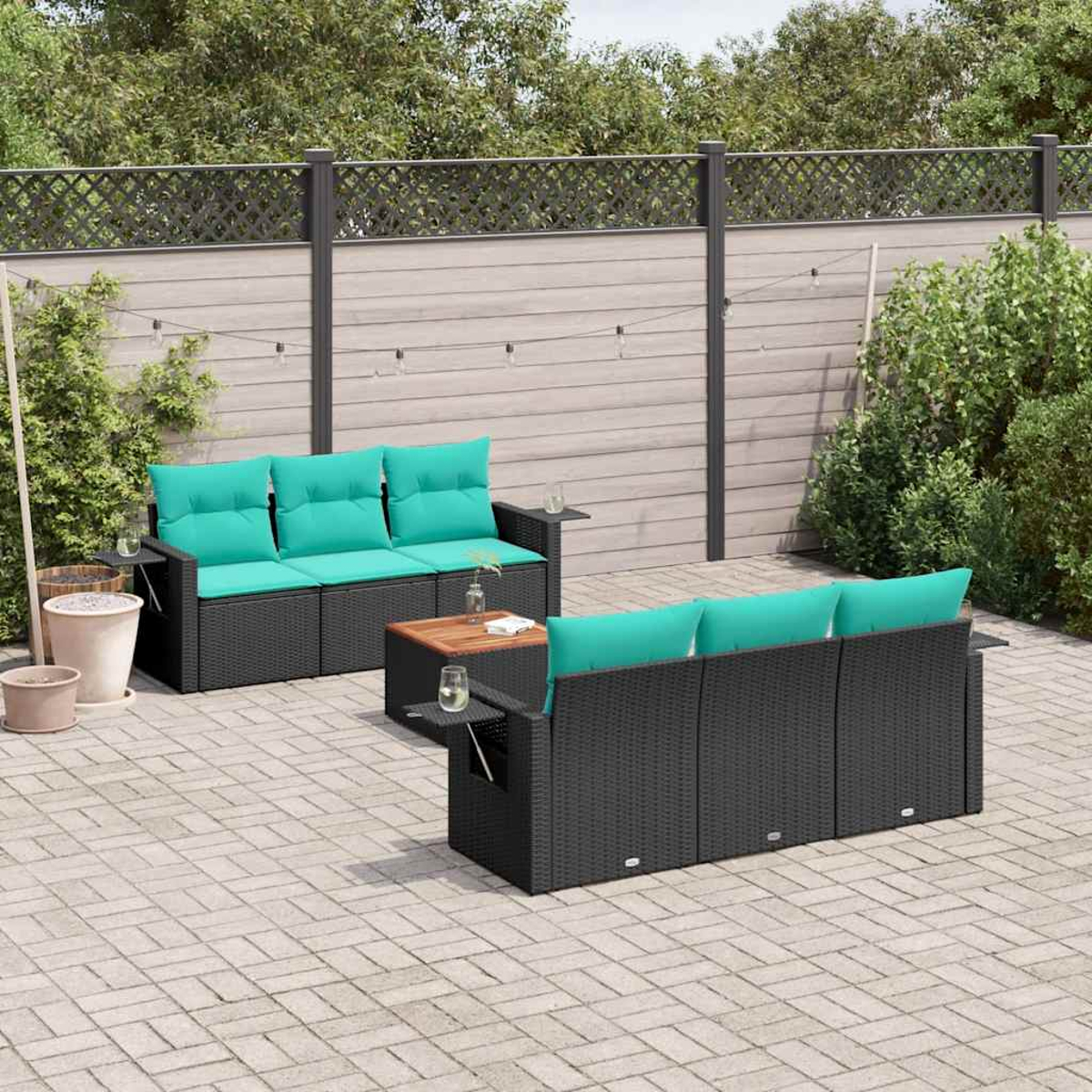 Garten-Set mit schwarzem Korbmöbeln, türkisfarbenen Kissen und einem Holztisch. Der Hintergrund ist ein Garten mit Zaun.