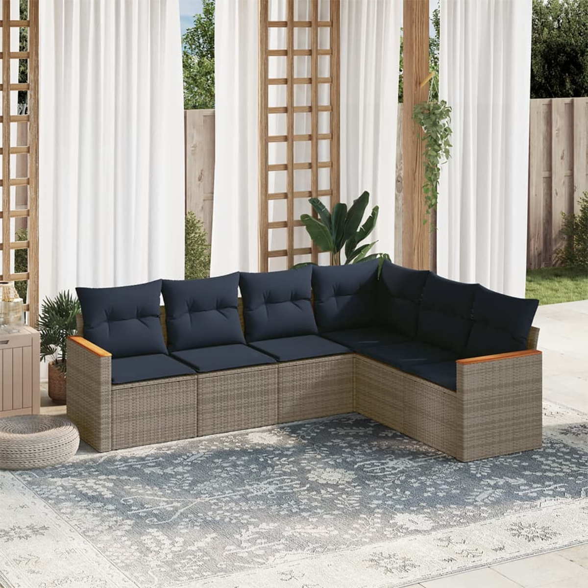 Ein Ecksofa mit marinefarbenen Kissen steht auf einem gemusterten Teppich. Weiße Vorhänge und Holzgitter im Hintergrund.