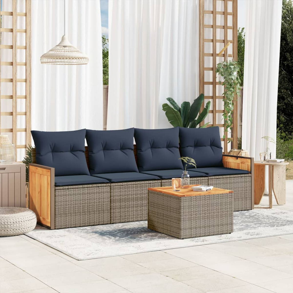 Gartenmöbel mit blauen Kissen, einem Couchtisch und einem Teppich. Weiße Vorhänge und eine Hängeleuchte im Hintergrund.