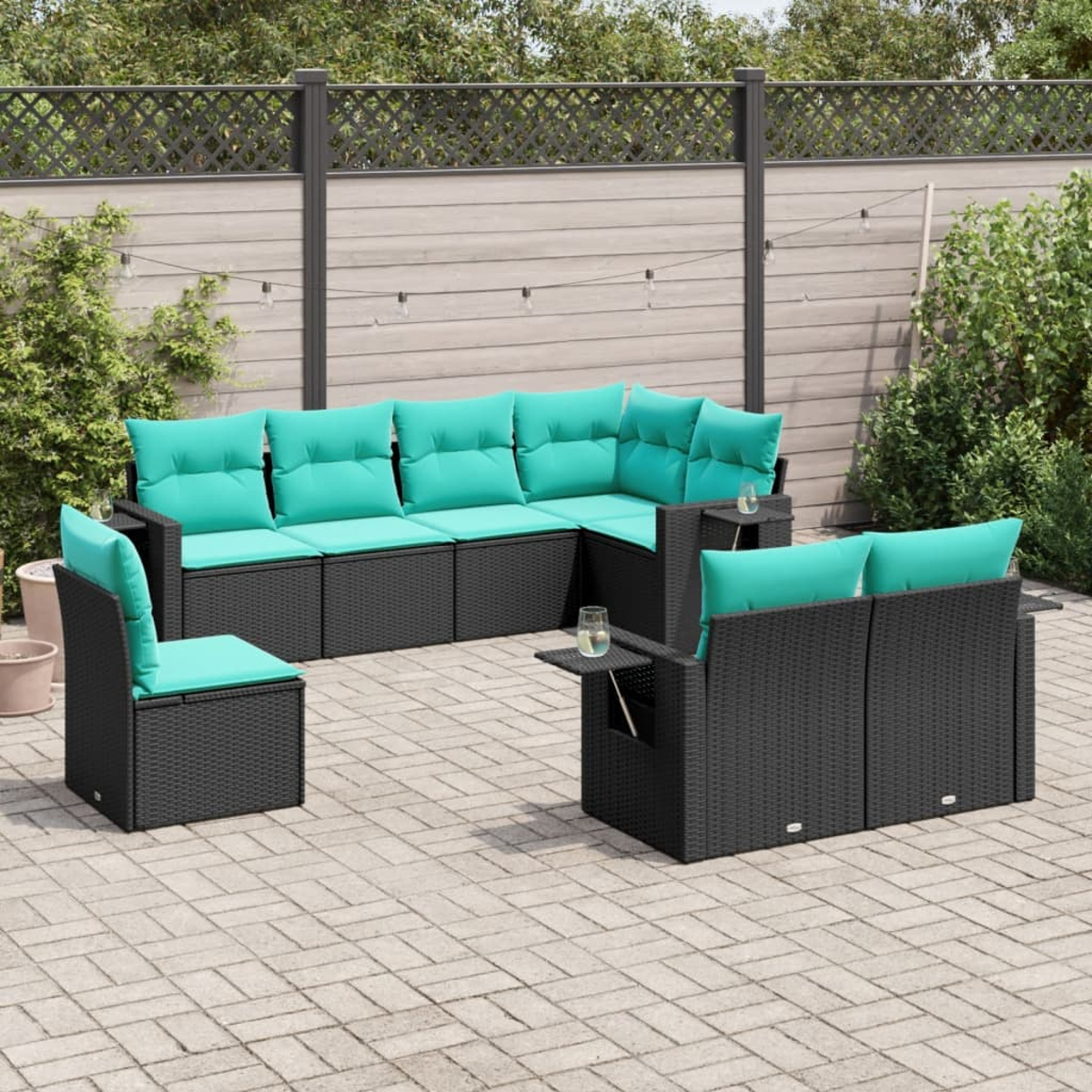 Garten-Terrassenset mit türkisfarbenen Kissen auf schwarzen Korbmöbeln. Enthält ein Ecksofa, Stühle und kleine Beistelltische auf einer Ziegelterrasse.