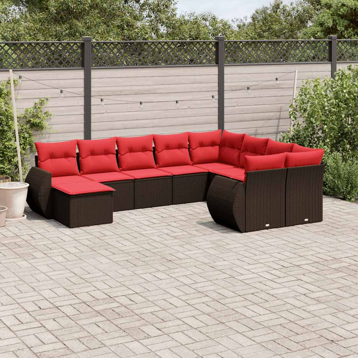 Ein Ecksofa mit roten Kissen im Freien steht auf einer Ziegelterrasse. Ein Zaun und Grün bilden den Hintergrund.