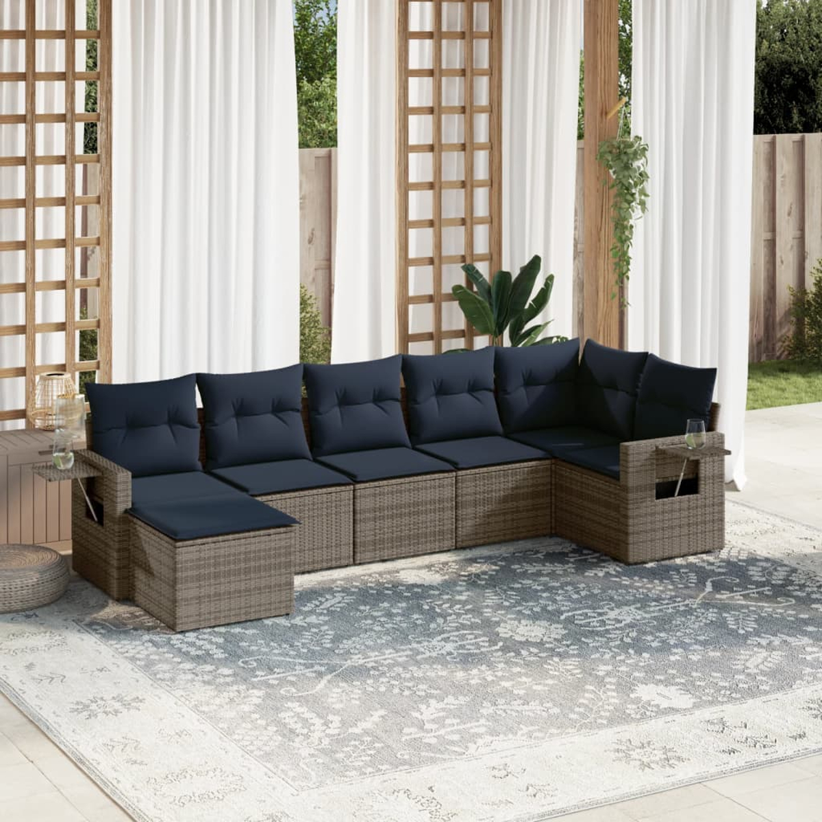 Ein Ecksofa mit marineblauen Kissen steht auf einem gemusterten Teppich. Weiße Vorhänge und Holzgitter befinden sich hinter dem Sofa.