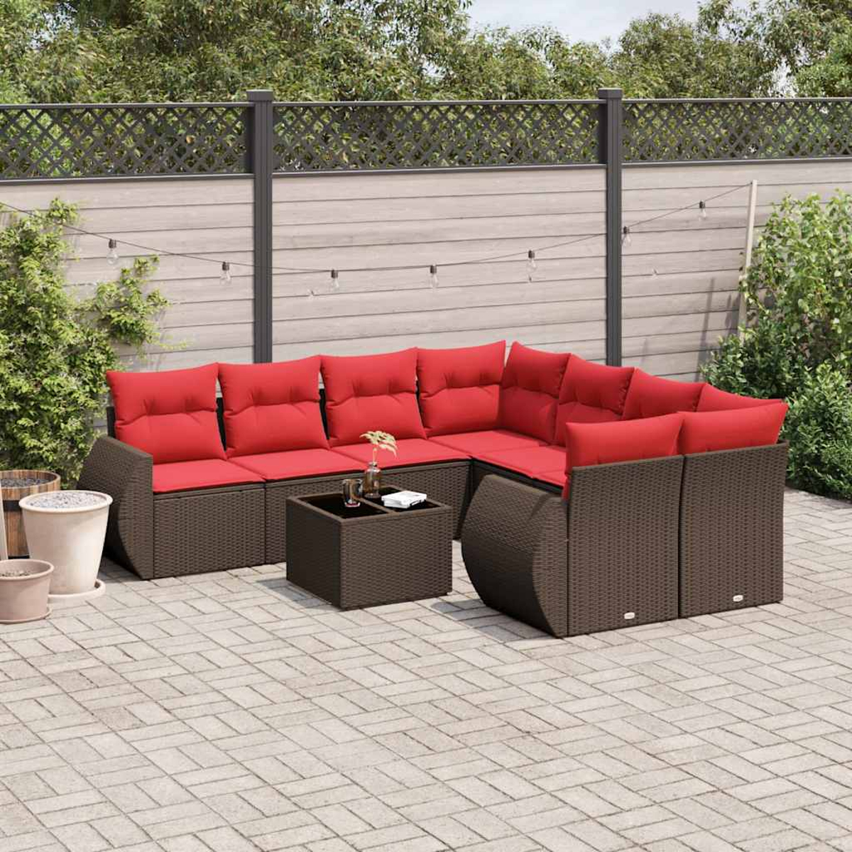 Ein Ecksofa im Freien mit roten Kissen, einem passenden Couchtisch und einer gepflasterten Terrasse. Der Hintergrund umfasst einen Zaun und Grün.