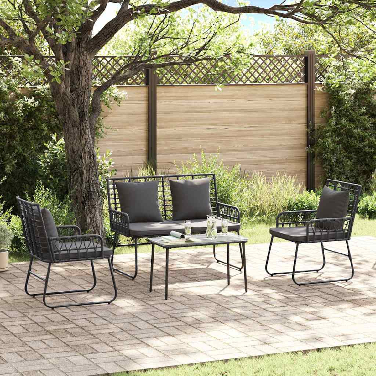 Gartenmöbel-Set mit schwarzem Metall, grauen Kissen und kleinem Tisch. Auf einer Backstein-Terrasse mit Holzzaun im Hintergrund.