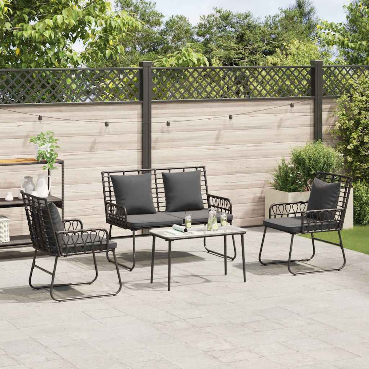 Terrassenset mit Sofa, zwei Stühlen und Tisch. Dunkelgraue Kissen und schwarze Metallrahmen. Holzzaun im Hintergrund.