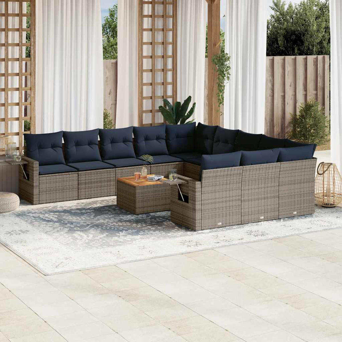 Outdoor-Ecksofa mit marineblauen Kissen und einem Holztisch auf einem gemusterten Teppich. Weiße Vorhänge und Holzgitter im Hintergrund.