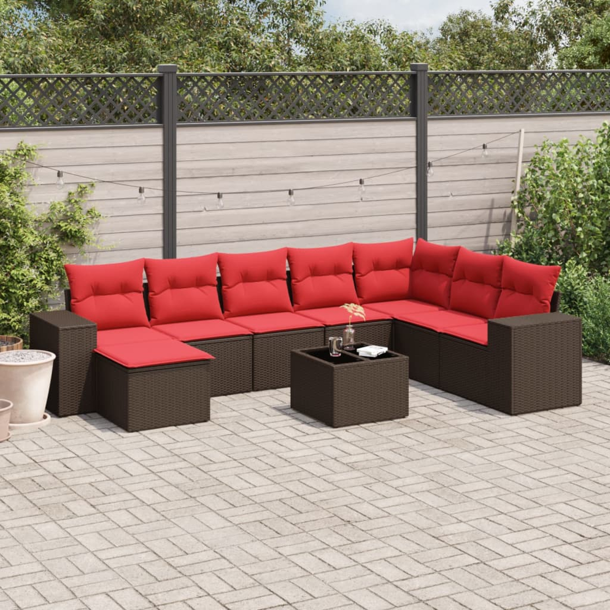 Garten-Sitzgruppe mit braunen Möbeln und roten Kissen. Ein kleiner Tisch und ein Zaun im Hintergrund.