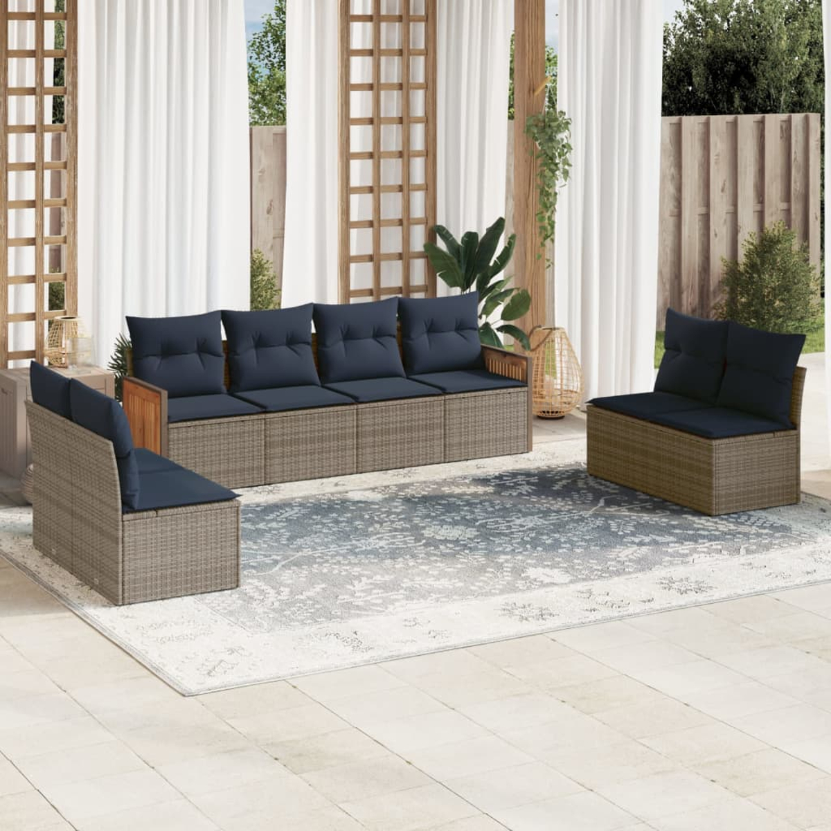 Gartenmöbel-Set mit Sofa und zwei Stühlen, marinefarbenen Kissen, auf einem gemusterten Teppich, Vorhängen und Pflanzen.