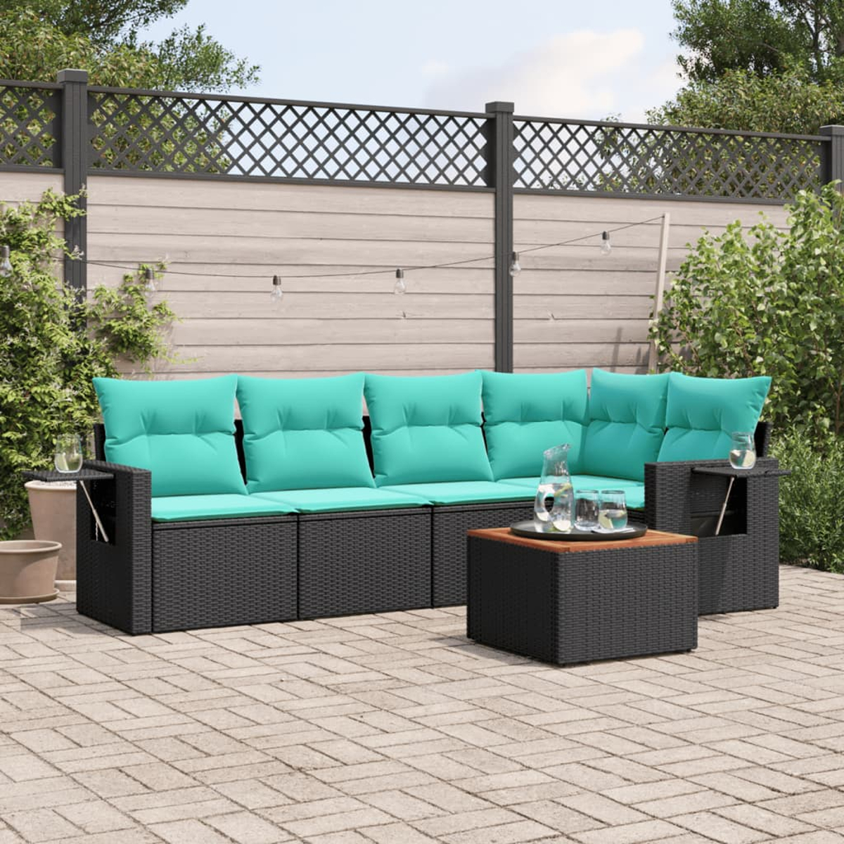 Outdoor-Ecksofa mit tealfarbenen Kissen, schwarzem Korbgewebe und einem kleinen Tisch. Auf einer Backstein-Terrasse mit einem Zaun im Hintergrund.