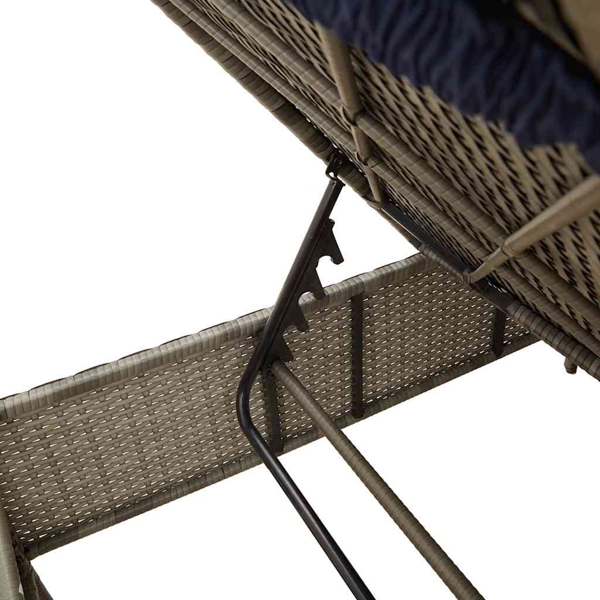 Primer plano de una silla de mimbre. El respaldo está levantado, sostenido por un marco de metal. Un cojín azul oscuro es visible en la parte superior.