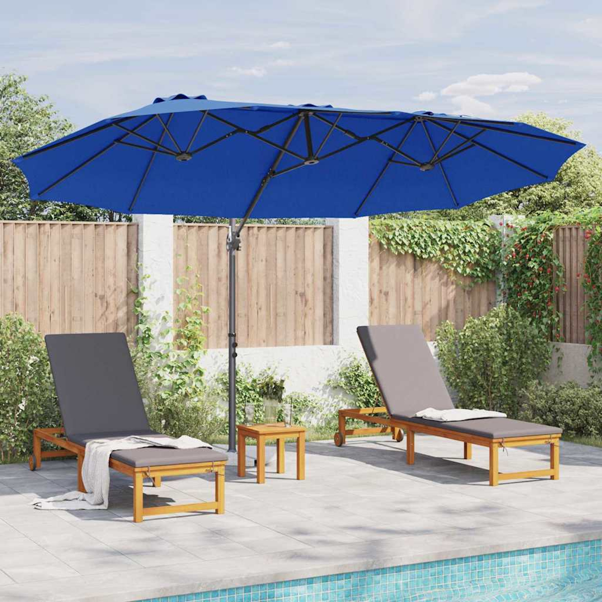 Due sedie a sdraio sotto un ombrello blu vicino a una piscina. Un tavolino è tra le sedie. Recinzione in legno e verde sullo sfondo.