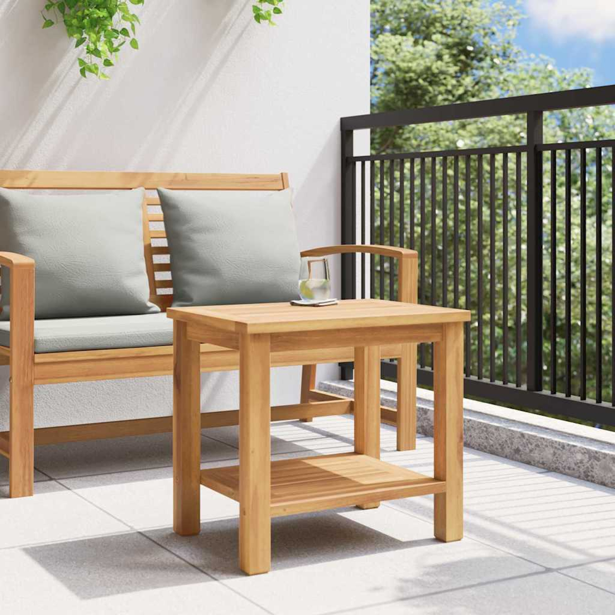 Escena exterior de madera con banco y mesa. Un vaso de agua en la mesa. Barandilla negra y follaje verde completan la escena.
