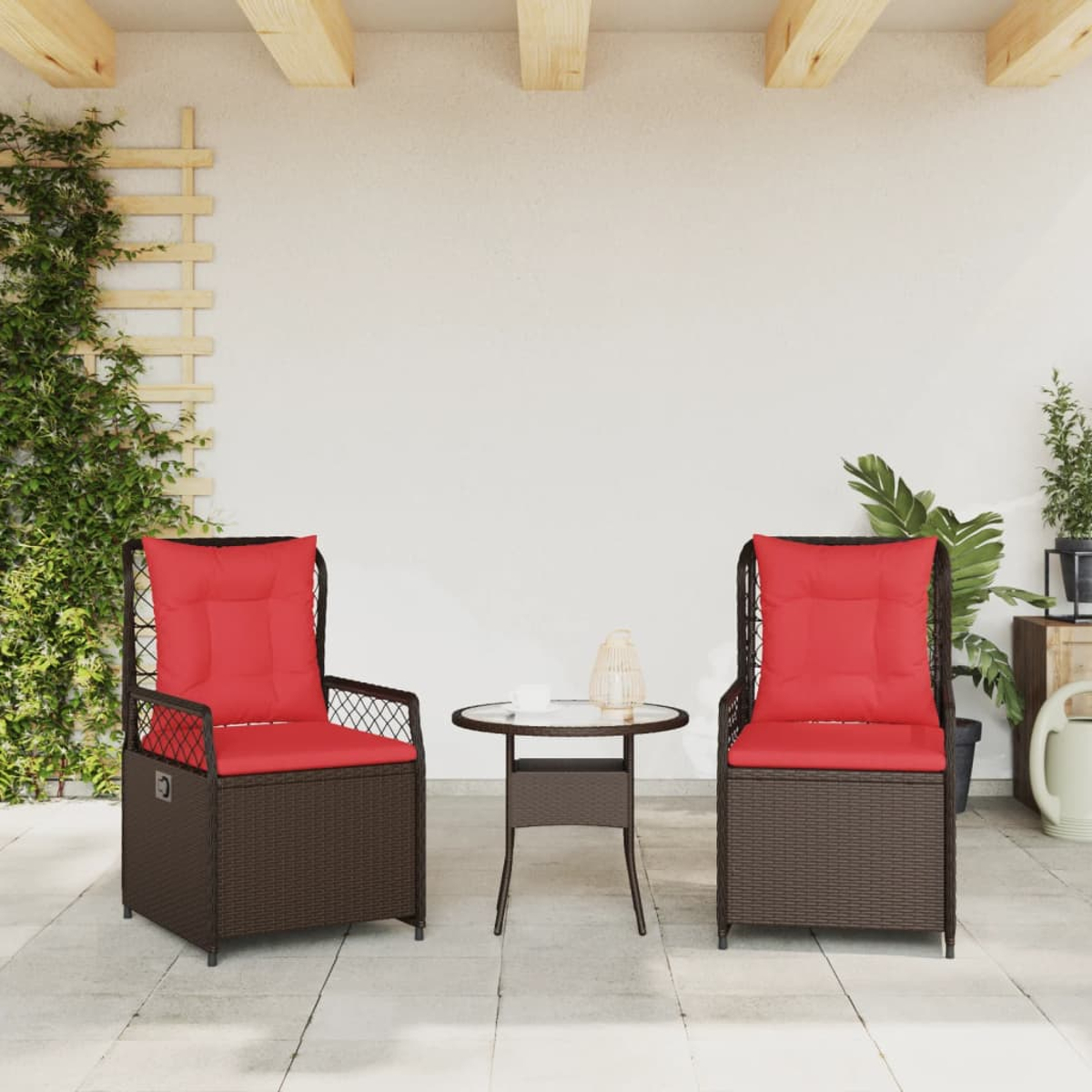 Zwei braune Korbstühle mit roten Kissen und ein kleiner Tisch auf einer Terrasse. Grüne Pflanzen im Hintergrund.