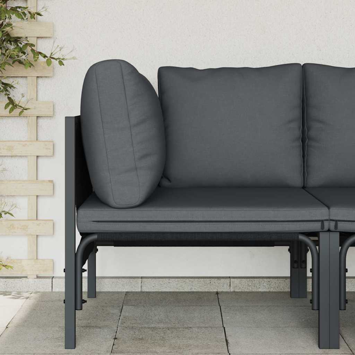 Graues Außensofa mit Kissen. Ein hölzernes Gitter und Laub sind im Hintergrund zu sehen. Das Sofa steht auf einer gefliesten Terrasse.
