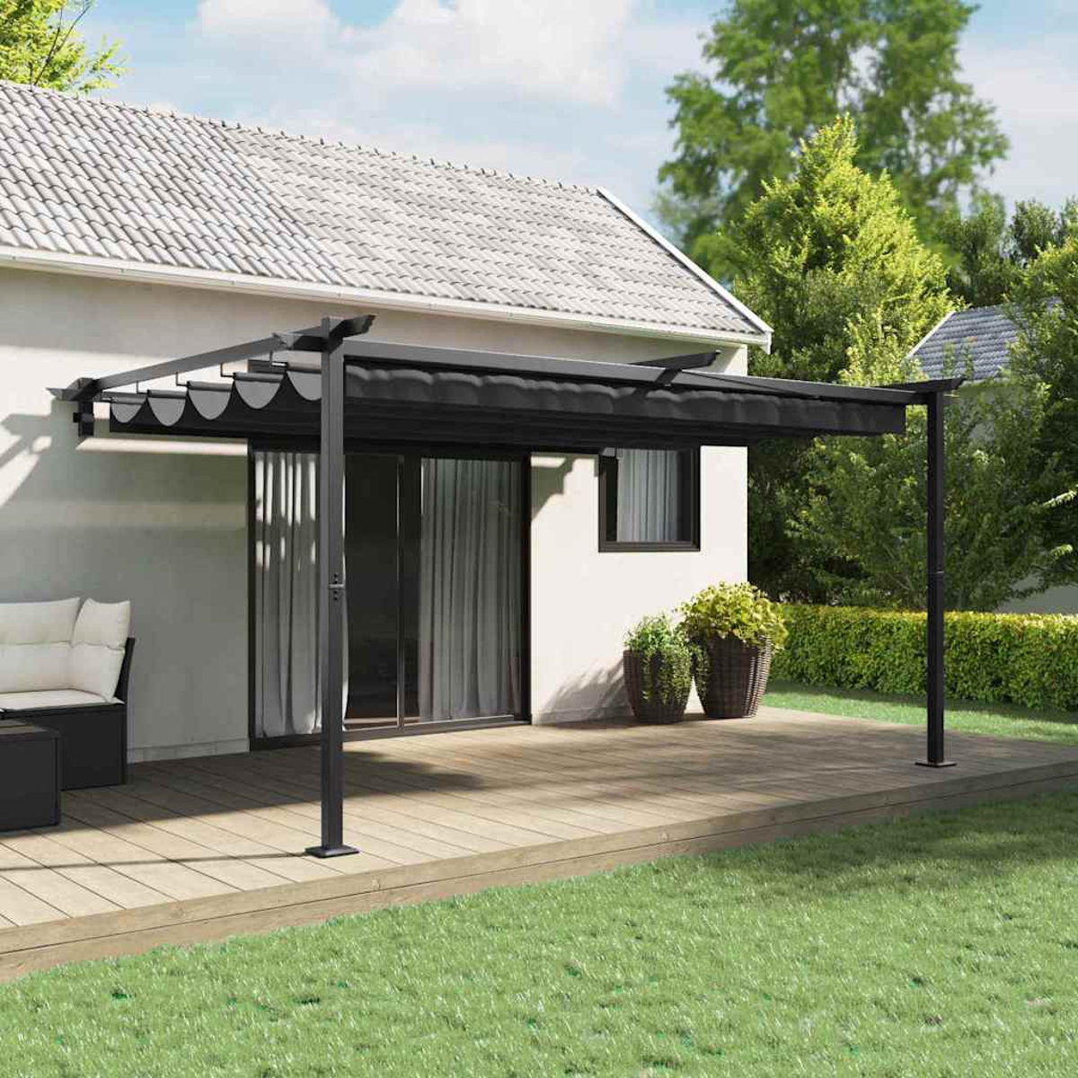 Eine schwarze Pergola bedeckt ein Holzdeck. Ein Haus mit weißer Fassade und grünem Gras im Vordergrund.