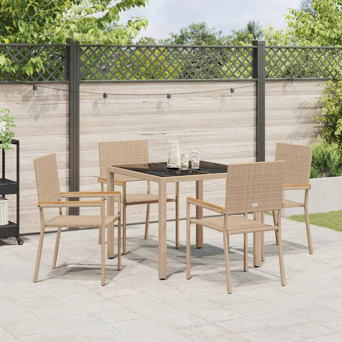 Terrassenset im Freien: Tisch mit vier Stühlen. Schwarze Tischplatte, beige Korbstühle. Hintergrund: Zaun und Grün.