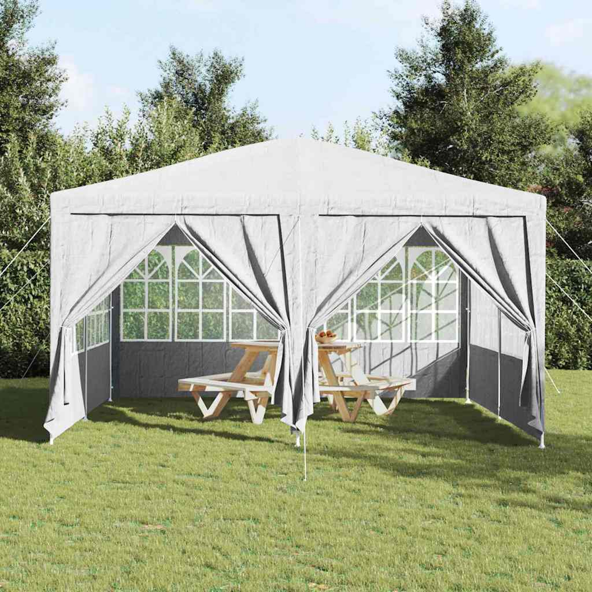 Una tenda grigia con i lati aperti è sull'erba. All'interno sono visibili due tavoli da picnic. Gli alberi sono sullo sfondo sotto un cielo blu.