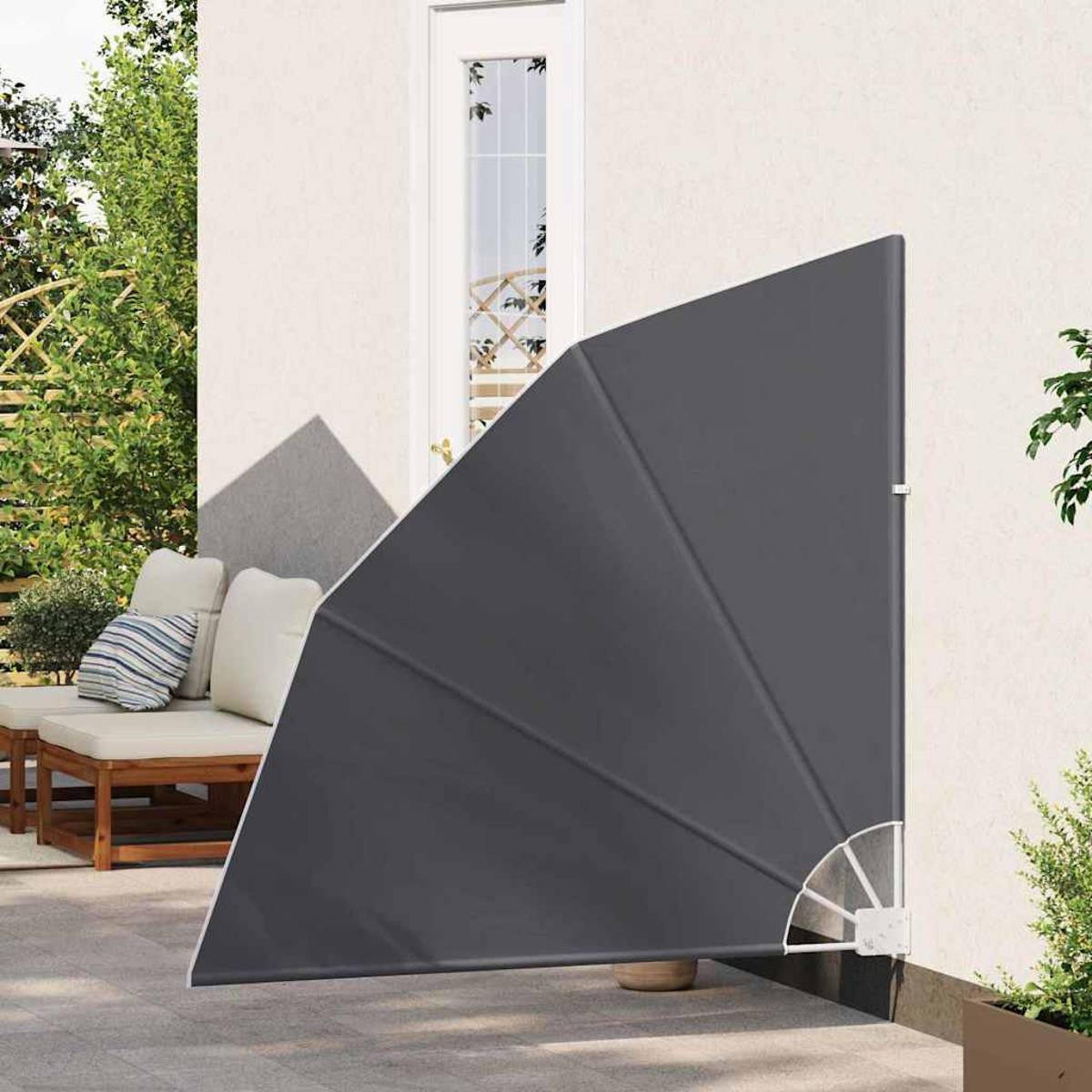 Eine graue Markise ist an einer weißen Wand angebracht. Im Hintergrund ist eine Tür zu sehen, und im Vordergrund eine Terrasse mit Möbeln.