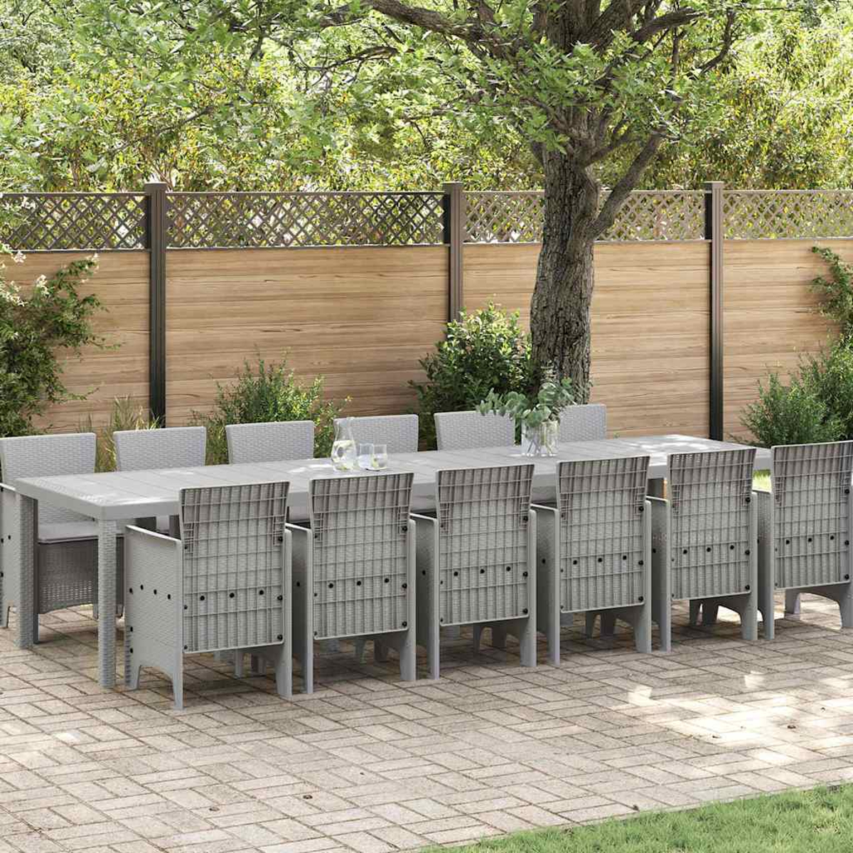 Juego de comedor al aire libre: una mesa rectangular gris con ocho sillas. Una valla de madera y árboles verdes al fondo.